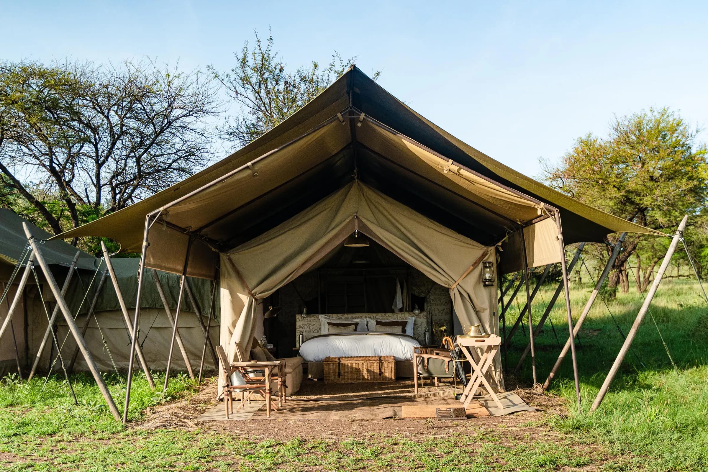 Canvas safari tent with a shaded front and bed inside